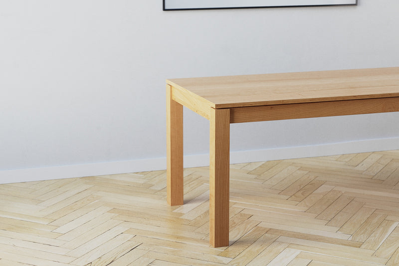 A handmade modern minimalist wooden dining table with square legs in an architectural style made from cherry wood.